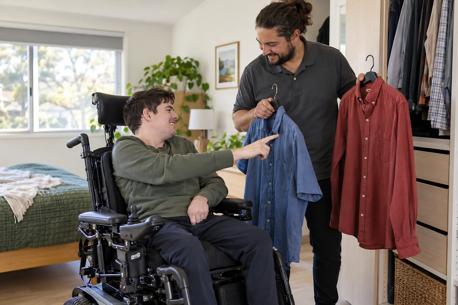 Young man in a power wheelchair choosing between two shirts that a support worker holds up in his bedroom